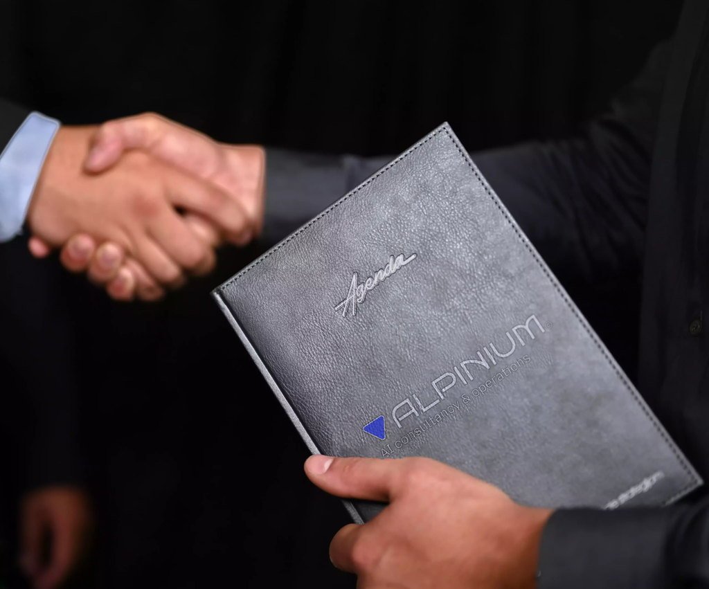 Alpinium agenda sa utisnutim logotipom u ruci konsultanta, tokom rukovanja sa klijentom u Beogradu